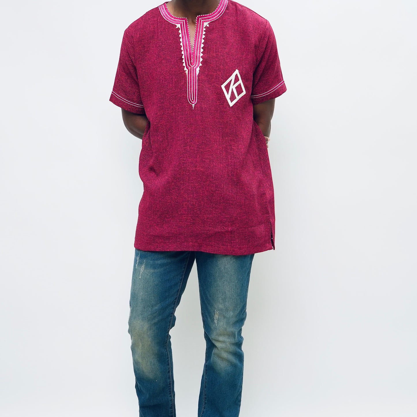 Person wearing a maroon embroidered shirt and blue jeans on a white background.The product is Kappa Alpha Psi African Wear, specifically designed for members of the prestigious African American fraternity. This apparel is a symbol of pride and unity among the members of the organization, showcasing their heritage and cultural background. With the iconic symbols and colors of Kappa Alpha Psi, this African wear is a must-have for any member looking to represent their fraternity in a stylish and meaningful way