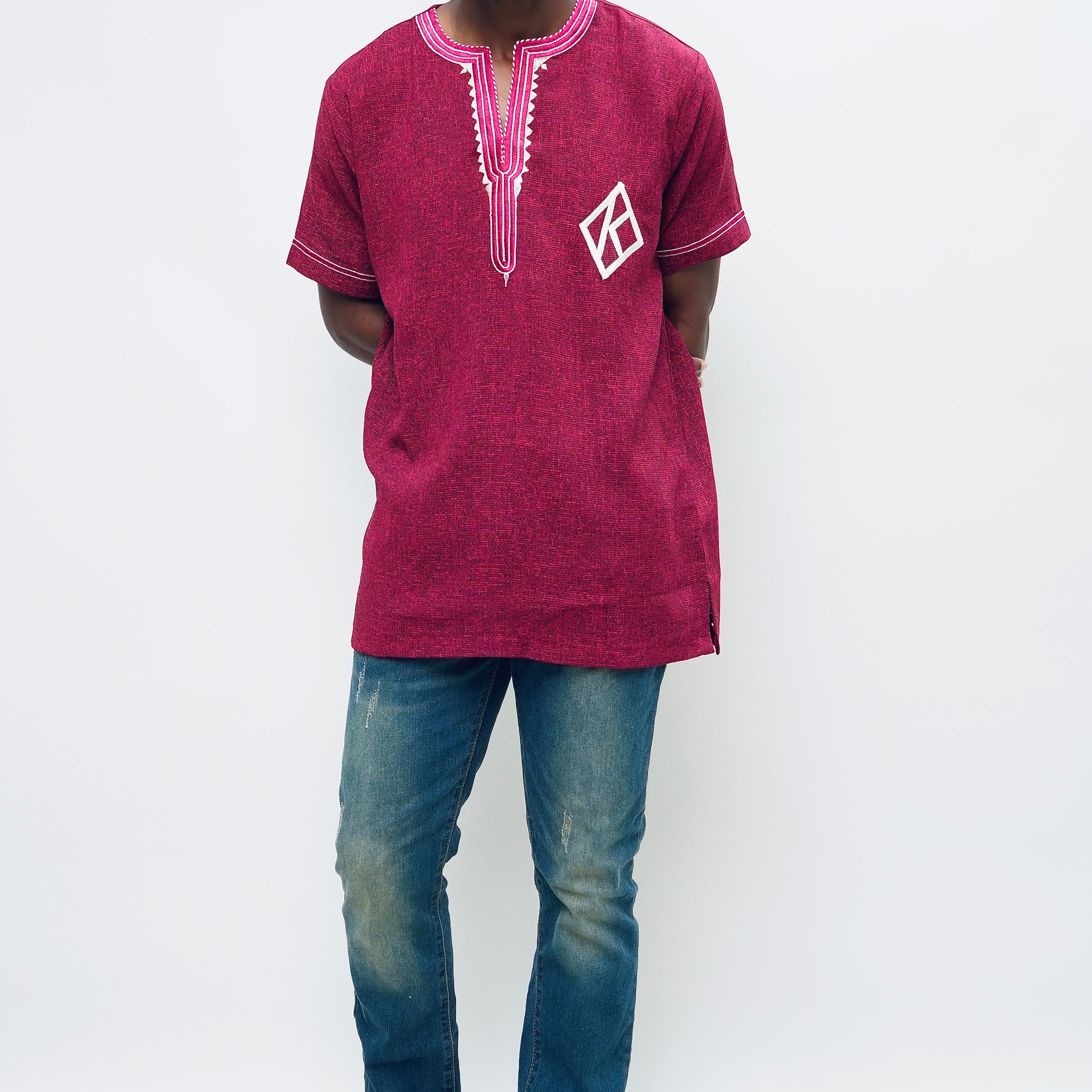 Person wearing a maroon embroidered shirt and blue jeans on a white background.The product is Kappa Alpha Psi African Wear, specifically designed for members of the prestigious African American fraternity. This apparel is a symbol of pride and unity among the members of the organization, showcasing their heritage and cultural background. With the iconic symbols and colors of Kappa Alpha Psi, this African wear is a must-have for any member looking to represent their fraternity in a stylish and meaningful way