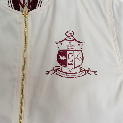 White jacket with a gold zipper and maroon crest design on the chest.The Kappa Alpha Psi Cream Twill Jacket is a stylish and classic outerwear option for men. Made with durable twill material, this jacket features the signature ivory/ cream color of the Nupe Kave brand. It is designed with regular sizing in mind, making it a versatile option for a variety of men's sizes. Perfect for adding a touch of sophistication to any outfit, this jacket is a must-have for any man looking to showcase.