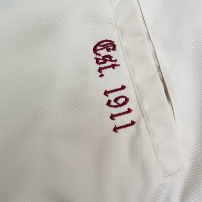Embroidered text 'Est. 1911' on a white background.The Kappa Alpha Psi Cream Twill Jacket is a stylish and classic outerwear option for men. Made with durable twill material, this jacket features the signature ivory/ cream color of the Nupe Kave brand. It is designed with regular sizing in mind, making it a versatile option for a variety of men's sizes. Perfect for adding a touch of sophistication to any outfit, this jacket is a must-have for any man looking to showcase their Kappa Alpha Psi pride in style.