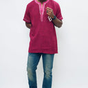 Person wearing a maroon embroidered shirt and blue jeans on a white background.The product is Kappa Alpha Psi African Wear, specifically designed for members of the prestigious African American fraternity. This apparel is a symbol of pride and unity among the members of the organization, showcasing their heritage and cultural background. With the iconic symbols and colors of Kappa Alpha Psi, this African wear is a must-have for any member looking to represent their fraternity in a stylish and meaningful way