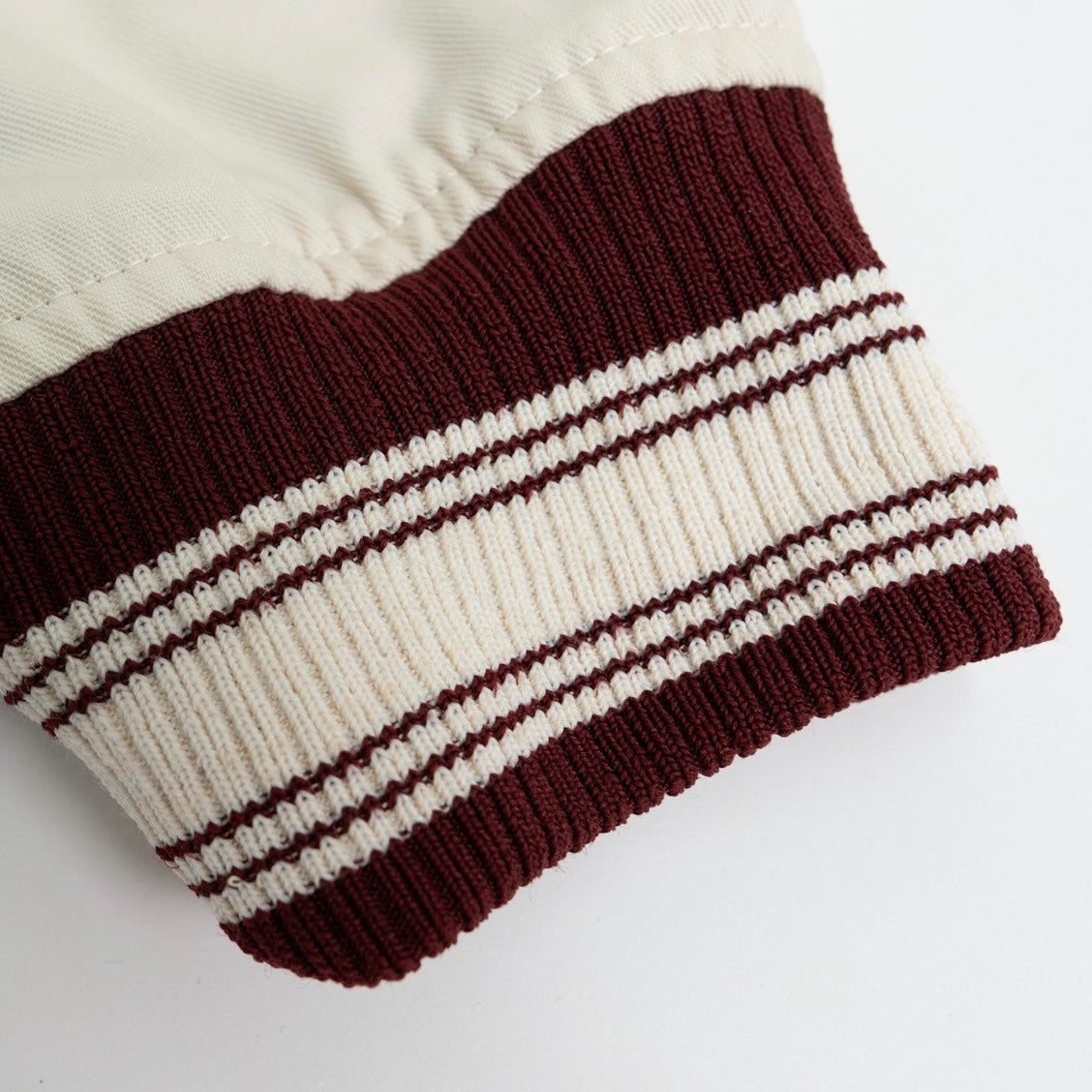 Close-up of a knitted item with brown and white stripes on a light background.The Kappa Alpha Psi Cream Twill Jacket is a stylish and classic outerwear option for men. Made with durable twill material, this jacket features the signature ivory/ cream color of the Nupe Kave brand. It is designed with regular sizing in mind, making it a versatile option for a variety of men's sizes. Perfect for adding a touch of sophistication to any outfit, this jacket is a must-have for any man looking to showcase.