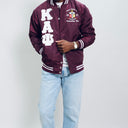 Person wearing a maroon letterman jacket with 'Kappa Alpha Psi' letters on a plain background.Check out our Kappa Alpha Psi satin jacket selection for the very best in unique design. This Kappa Alpha Psi Baseball Nylon Jacket shows the fraternity Shield embroidered on left chest and Greek letters on right to create style and unique comfort in wear. Quality beyond imagination.
